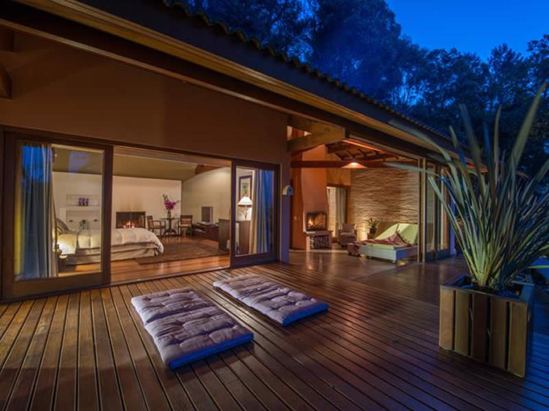 Morada Paraíso na hora azul, com deck iluminado e lareira interna